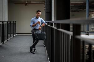 A handsome Asian businessman standing in the building corridor, taking a coffee break outdoors. photo