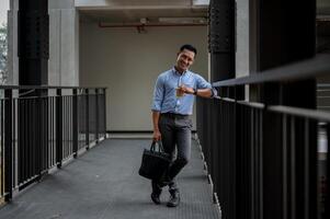 A handsome Asian businessman standing in the building corridor, taking a coffee break outdoors. photo