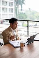 A confused Asian businessman is staring at his digital tablet screen with a puzzled expression. photo