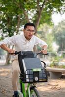 An anxious Asian businessman is in a hurry to get to work in the morning, riding a bike. photo
