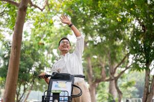 A happy businessman smiles and waves while pushing his bike, greeting someone while heading to work. photo