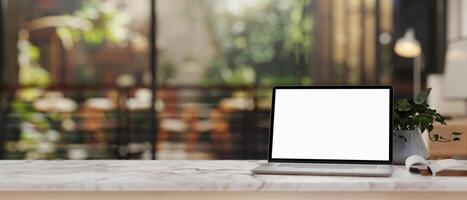 The white marble table featuring a computer mockup with a blurred background of an outdoor garden. photo