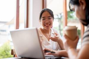 Two young Asian female college students are working on a project together, meeting at a coffee shop. photo