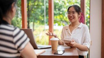 un positivo asiático mujer es teniendo un informal reunión con su cliente a un café tienda. foto