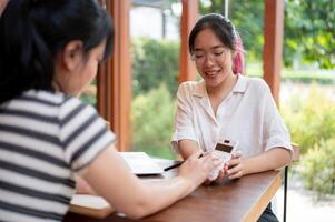 A young cheerful Asian female college student doing homework with her friend at a coffee shop. photo
