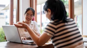 Two young Asian female college students are working on a project together, meeting at a coffee shop. photo