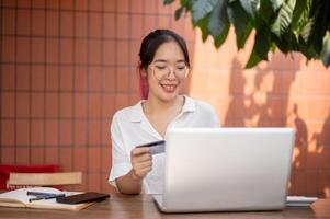 A young positive Asian woman is registering her credit card on a website, making an online payment. photo