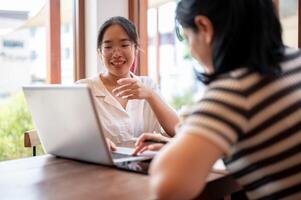 Two young Asian female college students are working on a project together, meeting at a coffee shop. photo