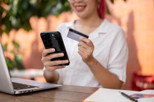 A woman using a mobile banking app, holding a smartphone and a credit card photo