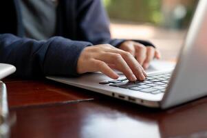 Close-up shot of a female freelancer working on her laptop computer at a table in her backyard. photo