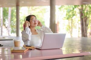 A happy Asian female college student is enjoying music on her headphones in her campus cafeteria. photo