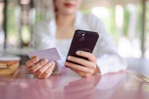 A cropped image of a female sits at a table in a cafeteria using a mobile banking app. photo