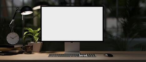 A modern home office desk at night with a white-screen computer mockup, dim light from a table lamp. photo