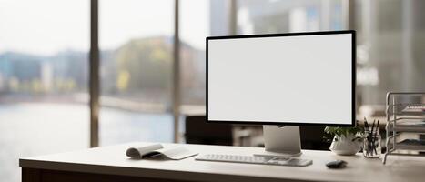 A modern office features a white-screen computer mockup and accessories arranged on a table. photo