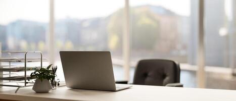 Back view image of a modern minimal bright office with a laptop computer on a white desk. photo