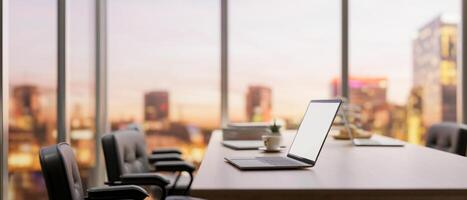 Side view image of a laptop on a meeting table in a modern company meeting room on a skyscraper. photo
