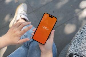 A close-up shot of a woman using the Payoneer application on her iPhone while sitting outdoor. photo