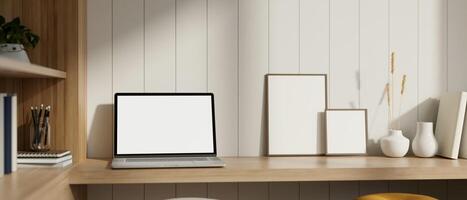 Home workspace with a white-screen laptop mockup and accessories on a wooden table. photo