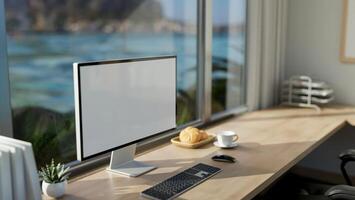 A modern office workspace with a computer mockup on a table against the window with a beach view. photo