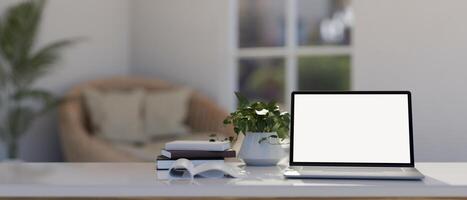 A white table with a white-screen laptop computer mockup in modern and comfortable living room. photo