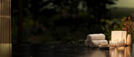 A copy space on a black marble table featuring towels, candles, a soap, and a lamp in a dark room. photo