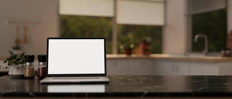 A laptop mockup on a black marble kitchen island countertop in a modern and clean kitchen. photo