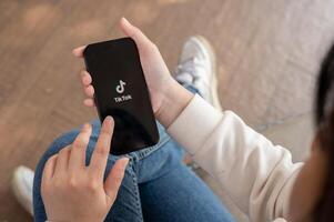 A close-up shot of a woman using the TikTok application on her iPhone while sitting outdoor. photo