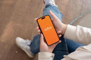 A close-up shot of a woman using the Payoneer application on her iPhone while sitting outdoor. photo