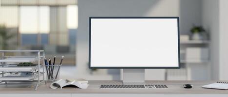 A modern, bright office with a white-screen computer mockup and office supplies on the desk. photo