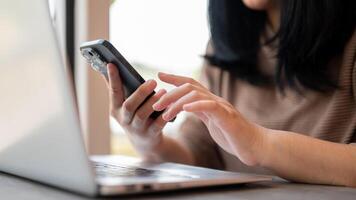 A woman using her smartphone, responding to messages while sitting in a cafe co-working space. photo