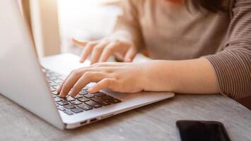 A woman working on her laptop computer in a cafe, typing on the laptop keyboard, responding to email photo