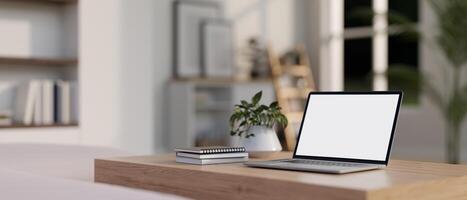 A white-screen laptop computer mockup on a wooden table in a modern white living room. photo