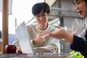 Two happy young Asian college students are discussing and working on a project in a cafe together. photo