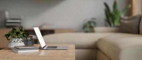 A laptop computer on a wooden coffee table in a modern and comfortable living room. side view photo