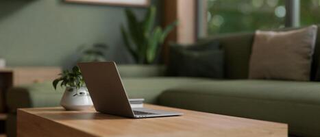 de cerca imagen de un ordenador portátil computadora en un de madera café mesa en un moderno vivo habitación en verde color. foto