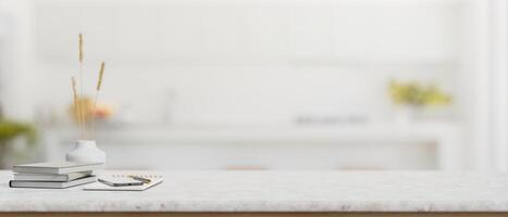 libros, un teléfono inteligente, un flor florero, y vacío espacio en un mesa en un moderno blanco cocina. foto