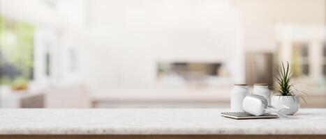 A book, headphones, a potted plant, and empty space on a tabletop in a modern white kitchen. photo