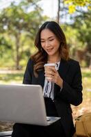 A beautiful Asian businesswoman is working remotely in a park in the afternoon. photo