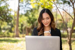 A beautiful Asian businesswoman is working remotely in a park in the afternoon. photo