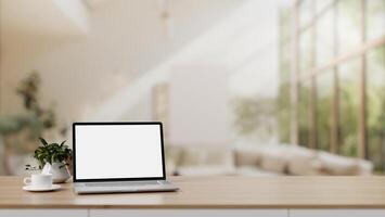 Home workspace, A white-screen laptop on a wooden table in a modern spacious living room. photo