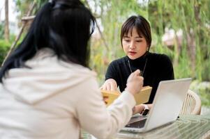 An Asian woman working remotely in a garden with her colleague, discussing work and sharing ideas. photo