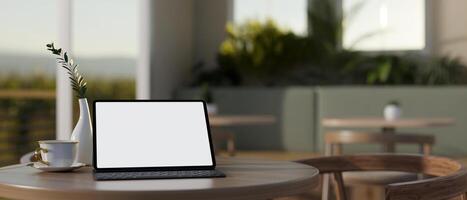 A white-screen digital tablet mockup on a wooden table in a contemporary coffee shop or restaurant. photo