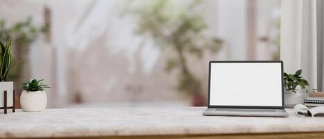 A white marble tabletop features a white-screen laptop computer mockup in a room with an indoor tree photo