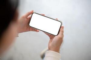 A woman holding a smartphone in a horizontal position, watching a or playing a mobile game. photo