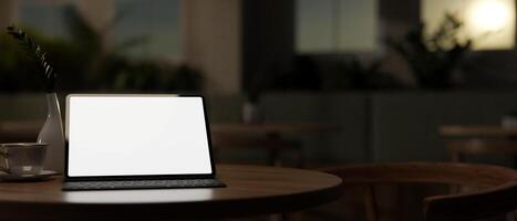 A close-up image of a digital tablet mockup on a wooden table in a dark room in the evening. photo