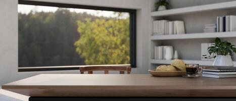 A copy space on a wooden table in a room with a bookshelf and a large window with a nature view. photo