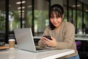 A female college student is using her smartphone while working remotely at a college's canteen. photo