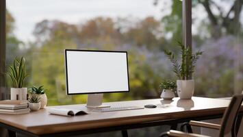 A computer mockup on a wooden desk against the large glass window with a nature view. photo