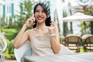 A beautiful Asian woman sits in a beautiful English garden talking on the phone with her friend. photo