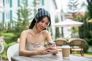 A beautiful Asian woman in a cute dress sits in a beautiful English garden using her smartphone. photo